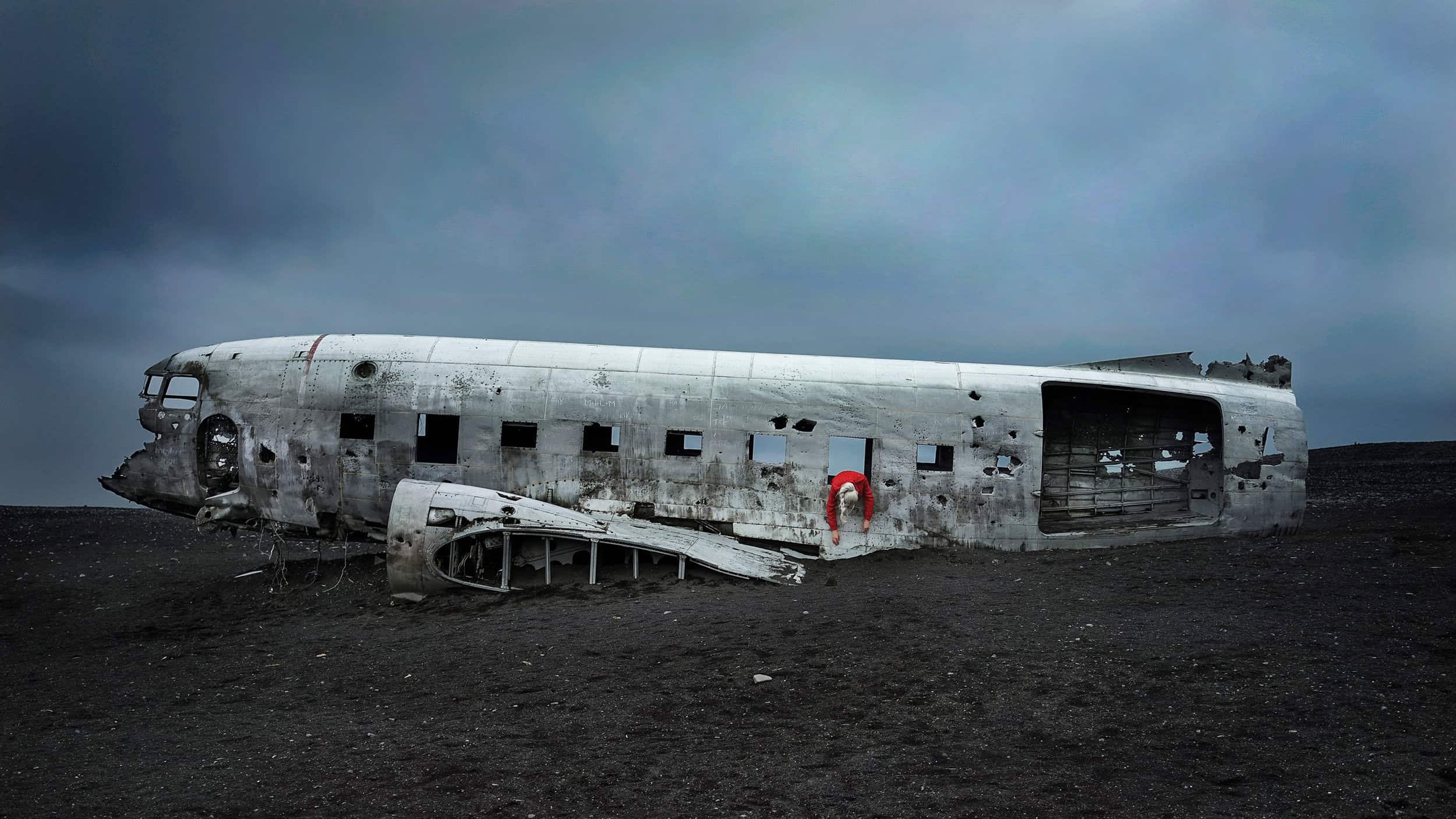 Fashion editorial in isceland with crashed plane. Red dress Garment: Sally LaPoint