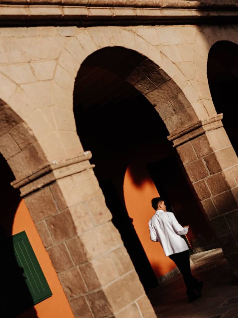 Man walking backwards towards a rustic style arch