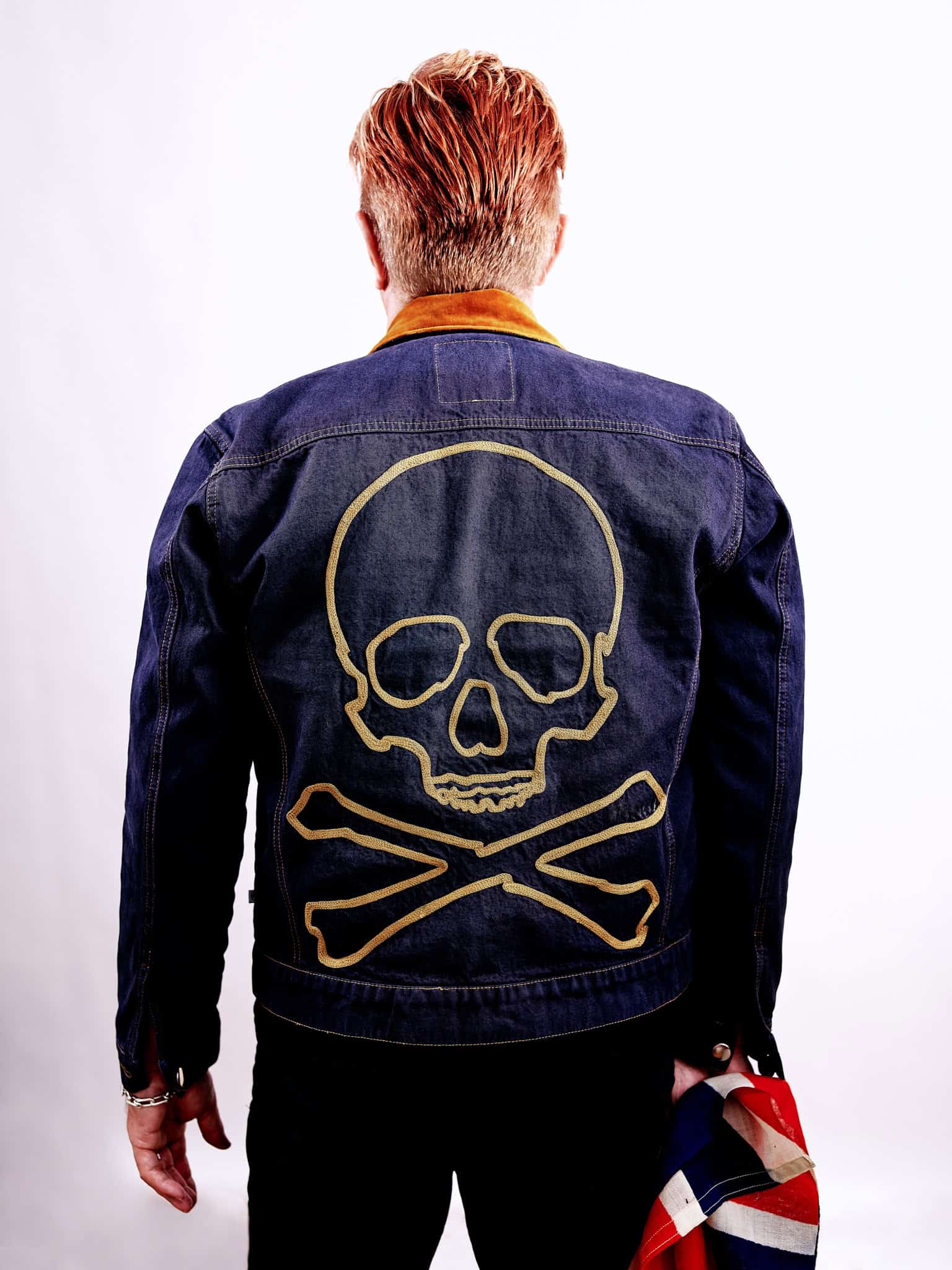 Keanan Duffy standing with skull jean jacket on and British flag in his hand